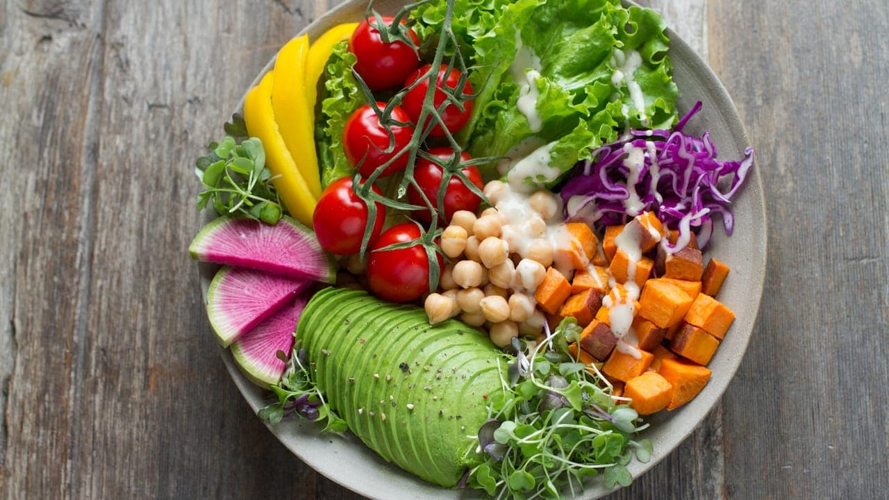 Colorful vegetarian meal bowls with fresh vegetables, grains, and legumes on a wooden table