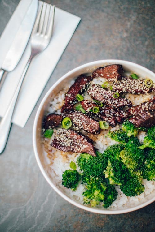 Beef and broccoli served over steamed white rice topped with sesame seeds and green onions