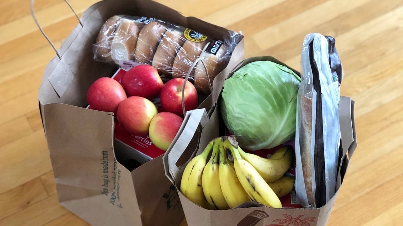 Grocery bags filled with affordable staples like rice, beans, chicken, and vegetables