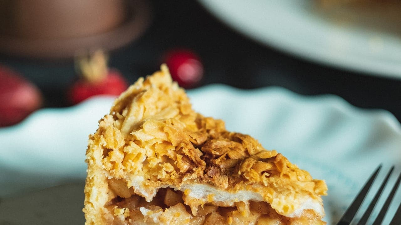 Golden baked apple crisp in a white baking dish with a scoop of vanilla ice cream on top