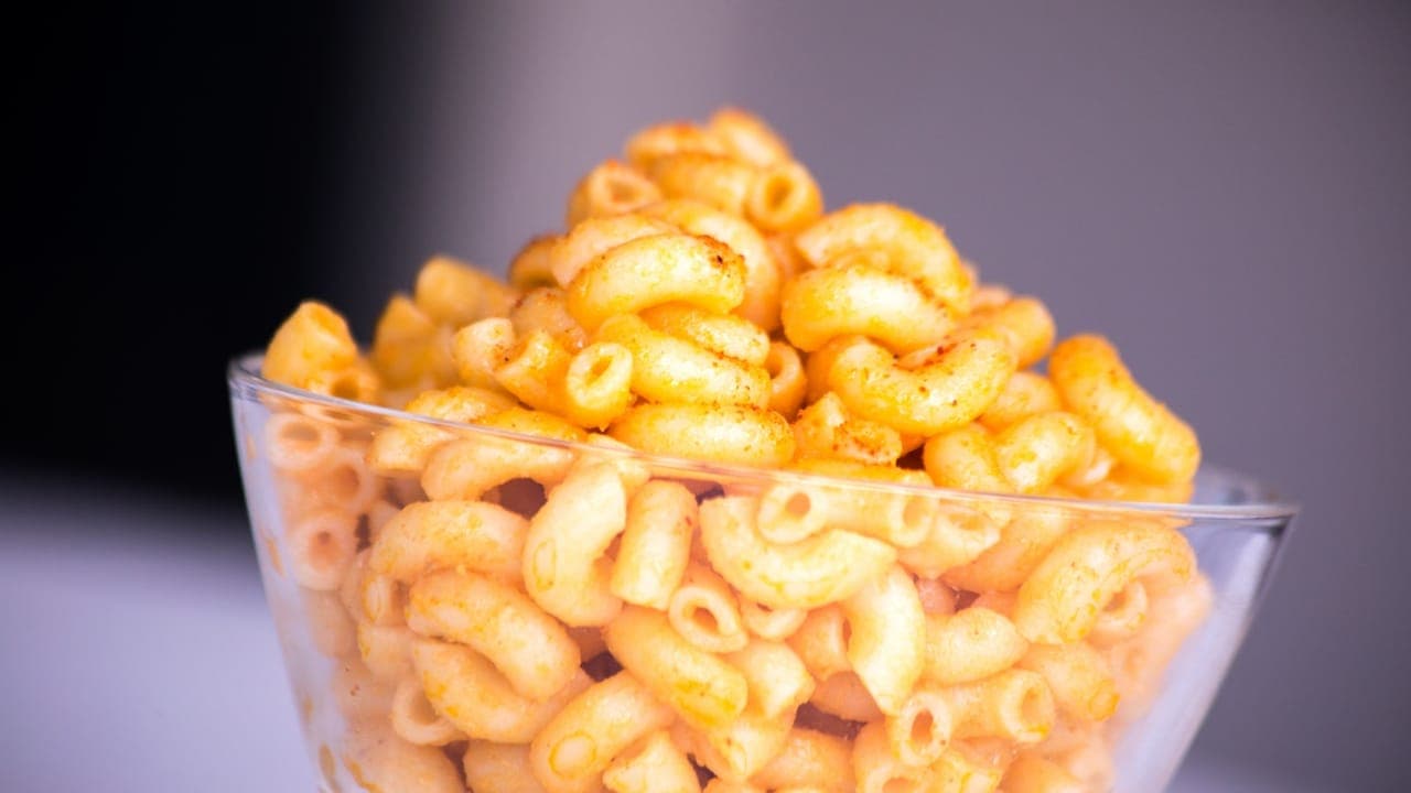 Golden baked mac and cheese in a casserole dish with a crispy breadcrumb topping and a spoon lifting out a cheesy scoop