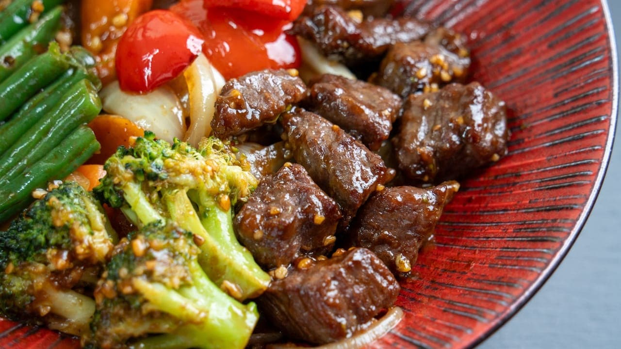 Beef and broccoli stir fry in a wok with glossy sauce served over white rice