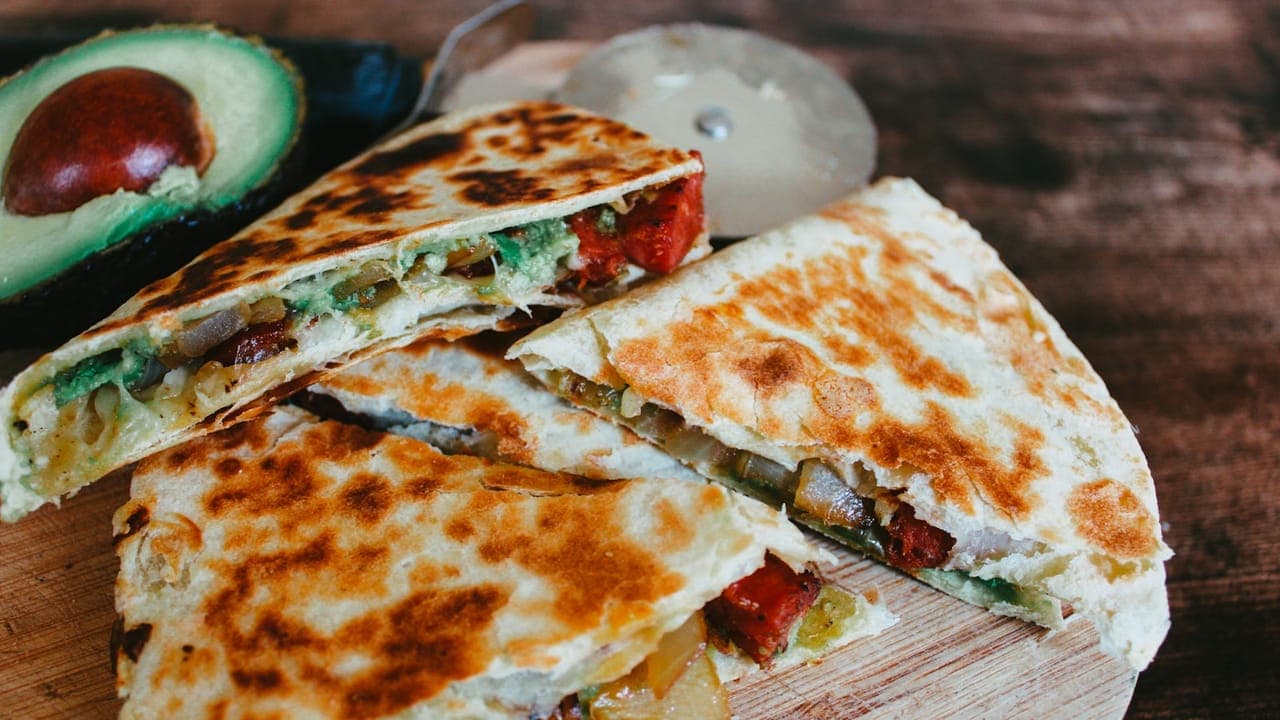 Crispy black bean quesadilla cut into wedges with melted cheese, served with salsa and sour cream