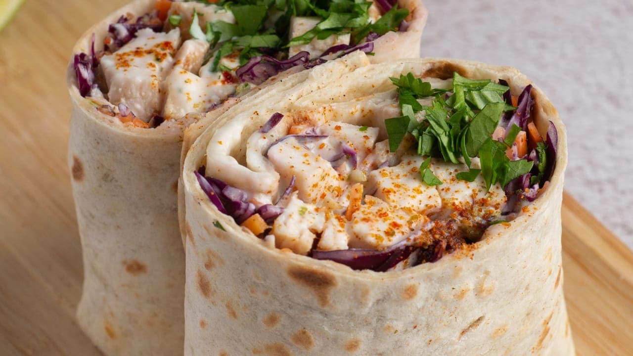 Golden breakfast burrito cut in half showing scrambled eggs, melted cheese, and diced potatoes