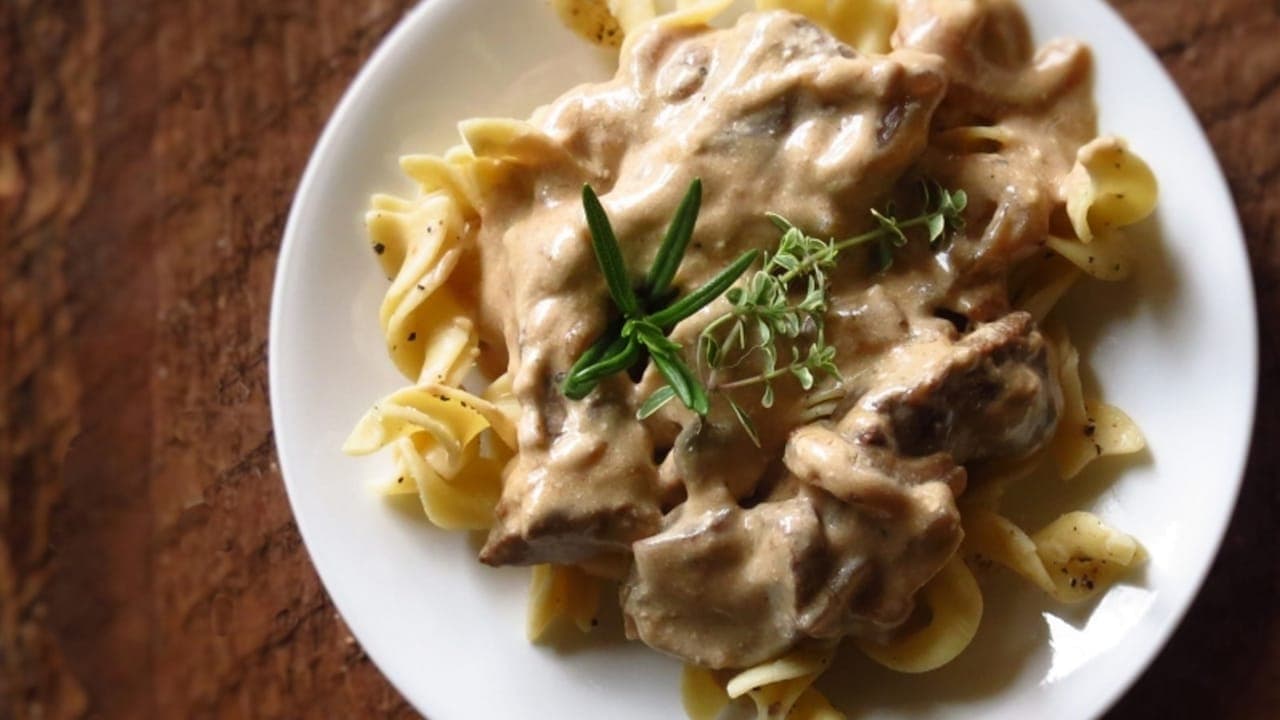 Creamy ground beef stroganoff served over egg noodles with parsley garnish
