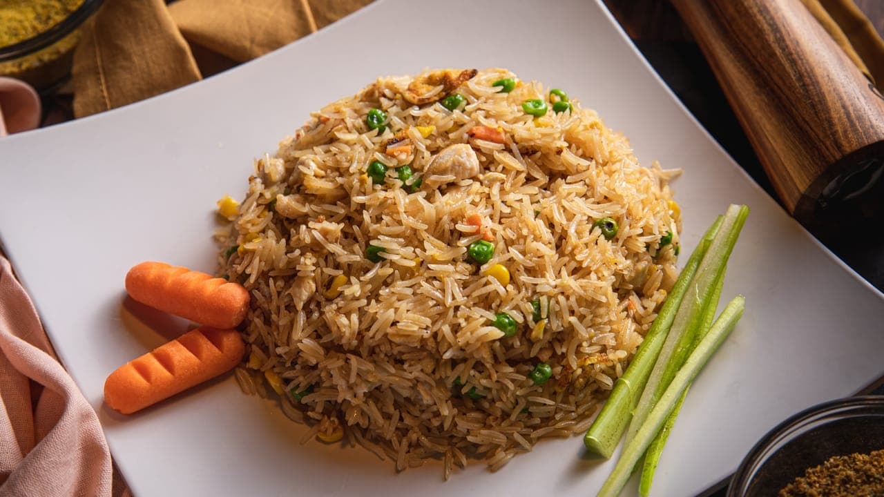 A bowl of chicken fried rice with colorful vegetables, scrambled eggs, and diced chicken