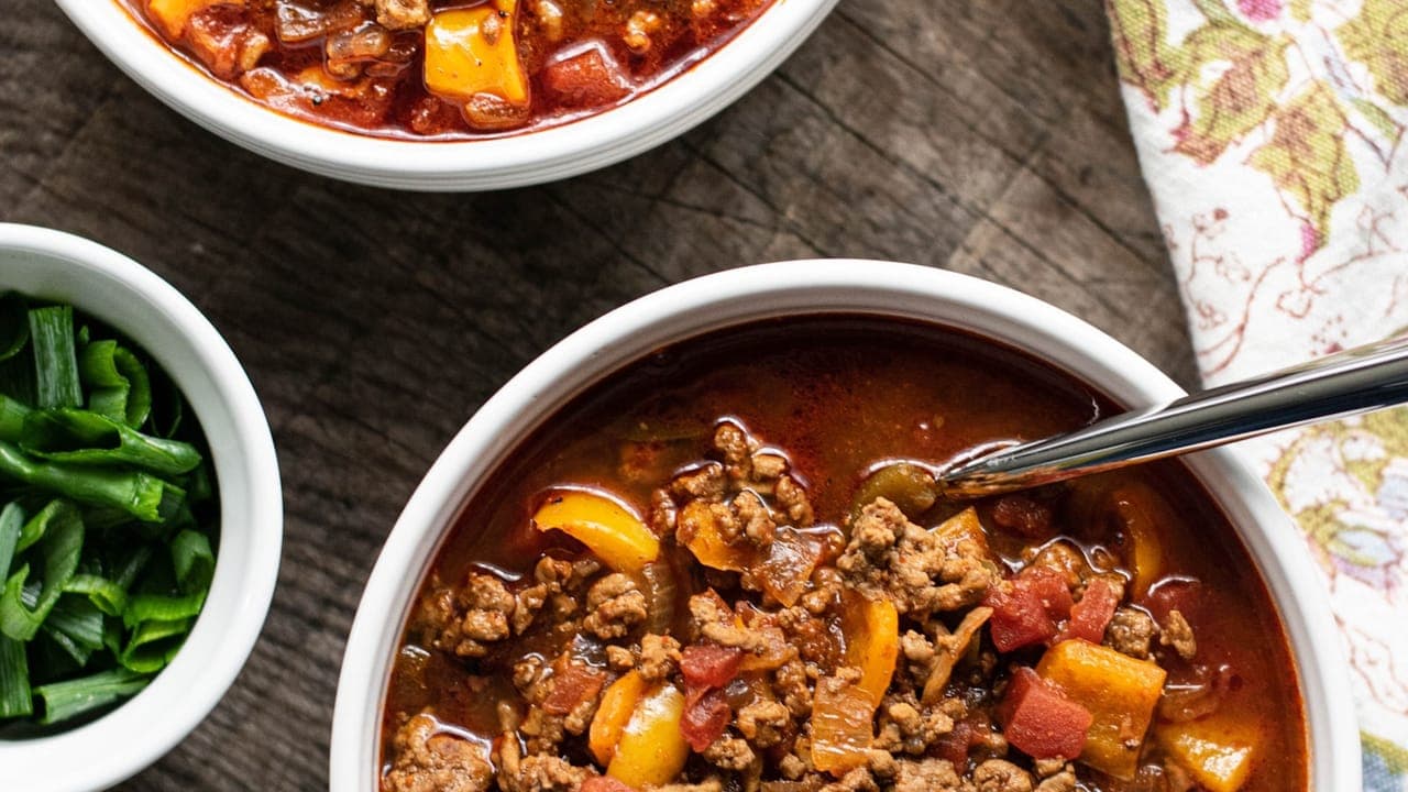 Bowl of classic beef chili topped with shredded cheese, sour cream, and crackers