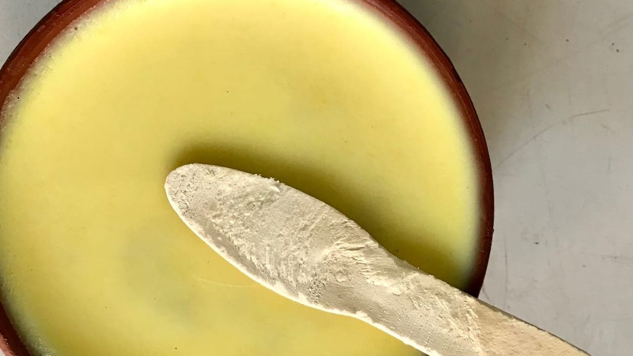 Bowl of creamy potato soup topped with shredded cheese, chives, and bacon bits