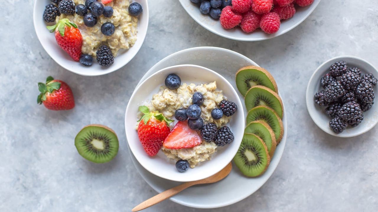 Mason jar of creamy overnight oats topped with fresh berries, sliced banana, and a drizzle of honey